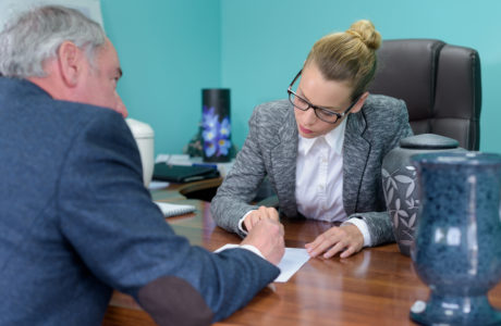 funeral director completing paperwork with senior man