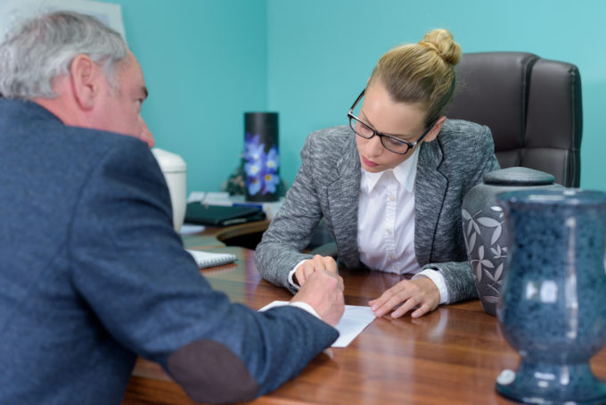 funeral director completing paperwork with senior man