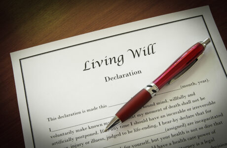 A document titled "Living Will" is laying on a table. On top of the document is a red pen.