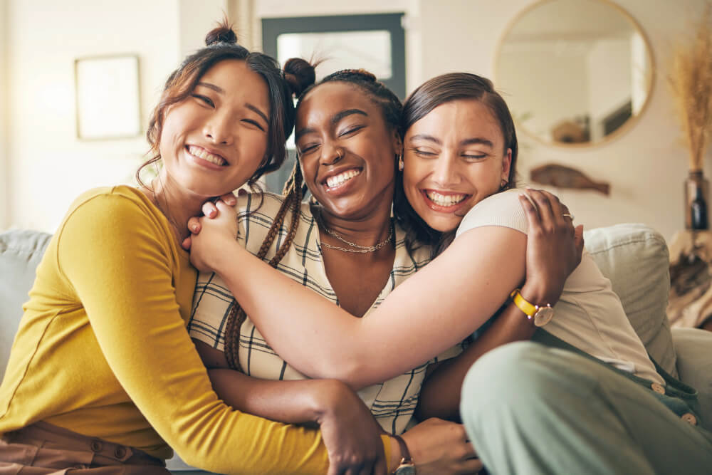 Friends smiling and hugging each other on a couch