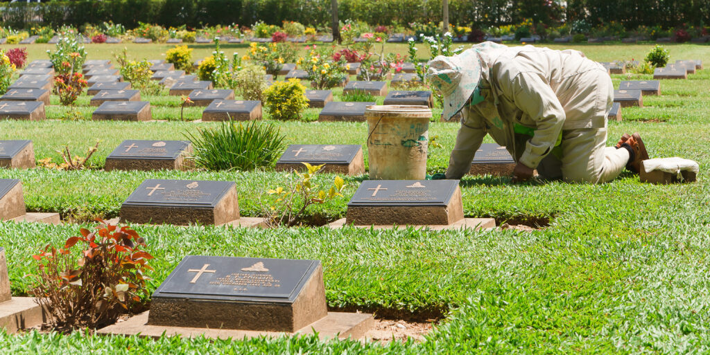 A person mourns on a grave site filled with slant headstones
